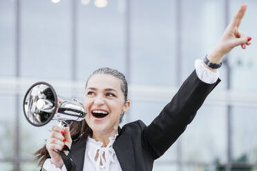 Happy mature woman with hand raised holding megaphone - IFRF01701