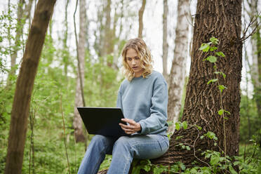 Schockierter Freiberufler schaut auf Laptop im Wald - MMIF00321