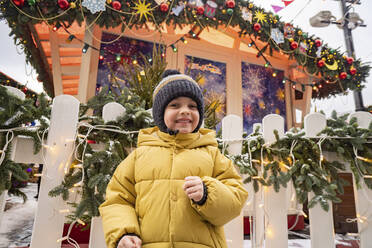 Niedlich lächelnder Junge mit Strickmütze auf dem Weihnachtsmarkt - SSGF00953