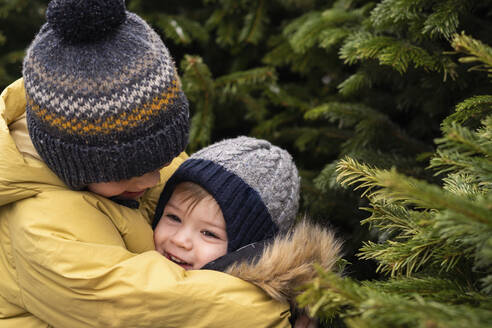 Brüder umarmen sich am Weihnachtsbaum - SSGF00958
