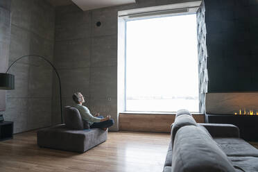 Senior man looking out of window in a loft flat stock photo