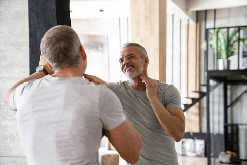 Smiling man admiring himself looking at mirror - VPIF06169