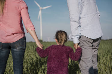 Girl holding parent's hands standing in field - MOEF04132