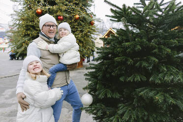 Glücklicher Vater mit Töchtern am Weihnachtsbaum - SIF00123