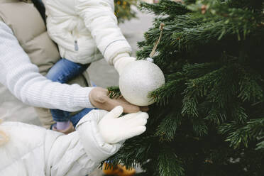 Vater und Töchter halten Weihnachtsschmuck am Baum - SIF00126