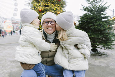 Töchter küssen Vater auf dem Weihnachtsmarkt - SIF00128