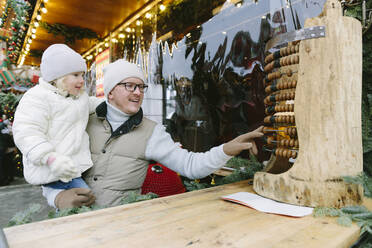 Father and daughter playing with abacus at Christmas market - SIF00134