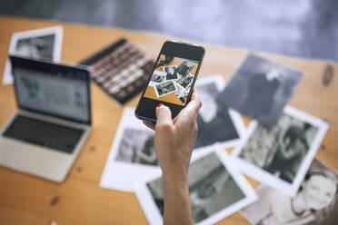 Hand einer Frau, die zu Hause mit ihrem Smartphone Fotos schießt - RFTF00201