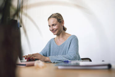 Lächelnde Geschäftsfrau mit Laptop zu Hause - RFTF00227