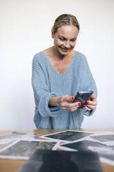 Lächelnde Frau beim Fotografieren von Fotos mit dem Smartphone - RFTF00234
