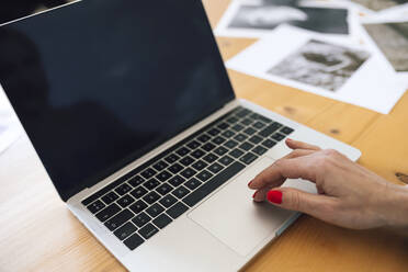 Hand einer Geschäftsfrau, die einen Laptop auf einem Tisch zu Hause benutzt - RFTF00237