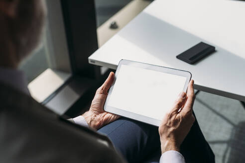 Älterer Geschäftsmann mit Tablet-PC am Schreibtisch sitzend im Büro - MEUF05786