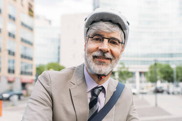 Happy businessman wearing cycling helmet - MEUF05843