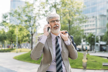 Businessman wearing eyeglasses talking on smart phone - MEUF05862