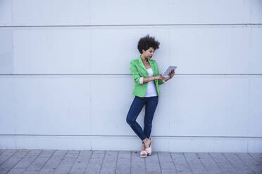 Afro-Frau mit Tablet-PC an die Wand gelehnt - UUF26220