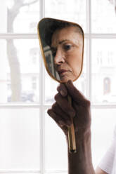 Reflection of worried senior woman in mirror at home - MASF29745