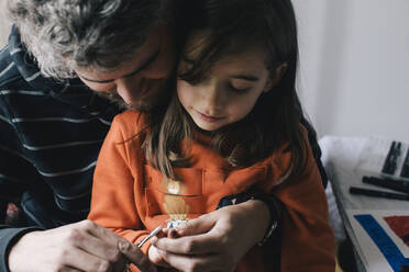 Father cutting nails of daughter with scissor at home - MASF29764