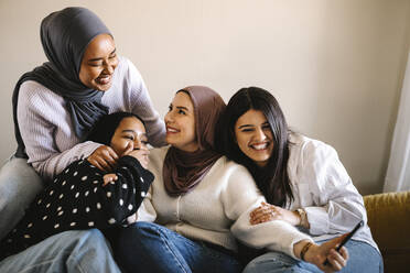 Fröhliche Frauen sitzen zu Hause auf dem Sofa - MASF29986