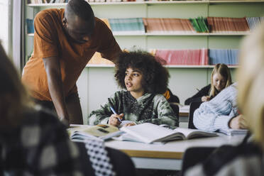 Männlicher Lehrer hilft einem Schüler beim Lernen im Klassenzimmer - MASF30015