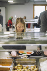 Mädchen nimmt während der Mittagspause in der Cafeteria Essen von der Essensausgabe - MASF30022