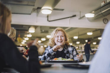 Lächelnder Junge mit Freunden während der Mittagspause in der Cafeteria der Schule - MASF30026