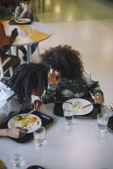 Junge tratschend mit Freund beim Essen während der Mittagspause in der Cafeteria - MASF30030