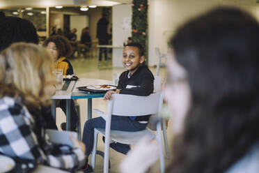 Seitenansicht eines Jungen, der während der Mittagspause in der Cafeteria der Schule auf einem Stuhl sitzt - MASF30031