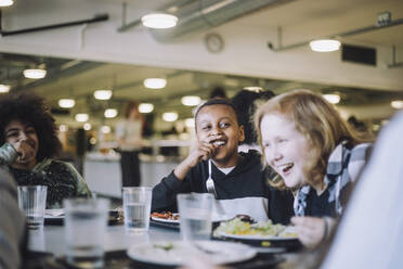 Lachende Freunde beim Essen am Tisch in der Mittagspause in der Cafeteria - MASF30039