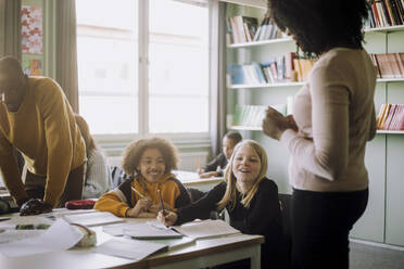 Lächelnde Schüler im Gespräch mit dem Lehrer im Klassenzimmer der Schule - MASF30053