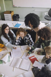 Hochformatige Ansicht eines Lehrers, der verschiedene Schüler im Klassenzimmer unterrichtet - MASF30066