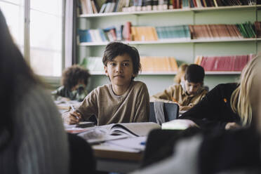 Porträt eines Jungen, der in einem Klassenzimmer auf dem Schreibtisch sitzt - MASF30070