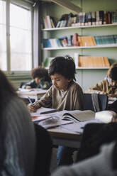 Junge, der auf dem Schreibtisch im Klassenzimmer sitzt und lernt - MASF30071