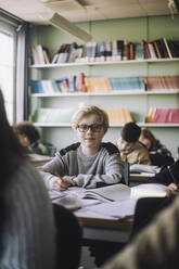 Boy wearing eyeglasses sitting at desk in classroom - MASF30072