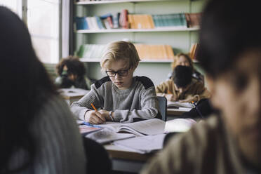 Pupil writing in book during exam in classroom - MASF30074