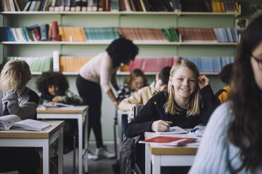 Porträt eines lächelnden Schülers, der am Schreibtisch im Klassenzimmer sitzt - MASF30078