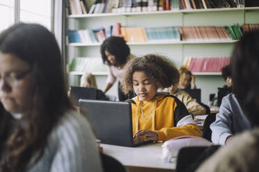 Mädchen mit Laptop am Schreibtisch beim Lernen im Klassenzimmer - MASF30084