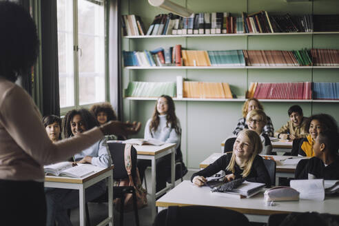 Zufriedene Schüler, die den Lehrer beim Unterrichten im Klassenzimmer beobachten - MASF30089