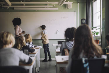 Ein Schüler löst eine mathematische Aufgabe an der Tafel im Klassenzimmer - MASF30093