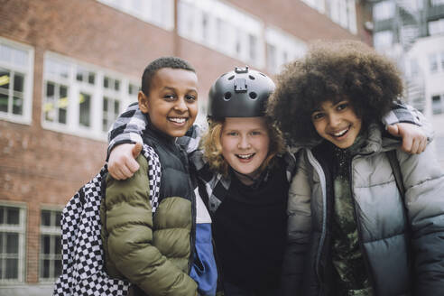 Porträt von glücklichen Freunden, die zusammen vor einem Schulgebäude stehen - MASF30123