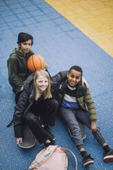 High angle view of friends sitting on ground in sports court - MASF30129