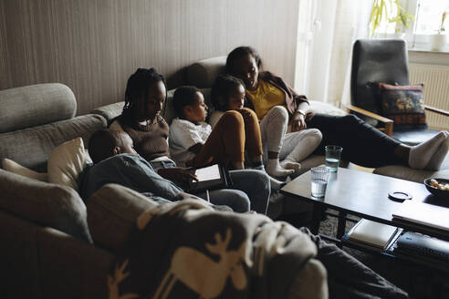 Vater und Mutter entspannen sich mit ihren Kindern auf dem Sofa im heimischen Wohnzimmer - MASF30274