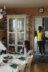 Girl talking with brother while sitting at dining table - MASF30296