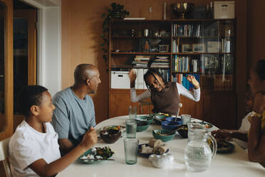 Fröhliches Mädchen genießt das Essen mit der Familie am Esstisch - MASF30302