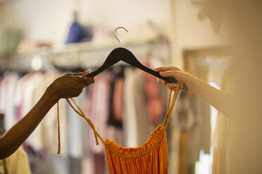 Frau, die einer Kundin in einem Geschäft ein Kleid auf einem Kleiderbügel überreicht - CAIF32671