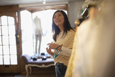 Smiling female shop owner with face mask in boutique - CAIF32676