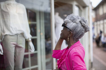 Ältere Frau beim Schaufensterbummel in einer Bekleidungsboutique - CAIF32684