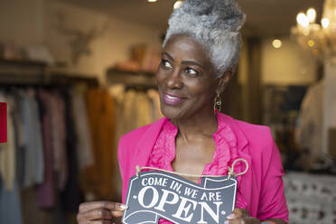 Porträt einer selbstbewussten Geschäftsinhaberin mit offenem Schild in einer Boutique - CAIF32688