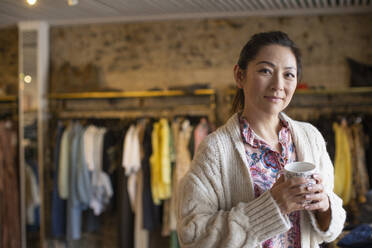 Porträt einer selbstbewussten Ladenbesitzerin mit Tee in einer Boutique - CAIF32698