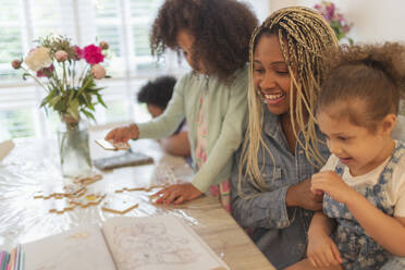 Glückliche Mutter und Töchter beim Malen und Spielen am Tisch - CAIF32709