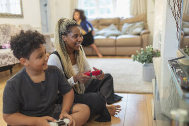 Mutter und Sohn spielen ein Videospiel auf dem Wohnzimmerboden - CAIF32711